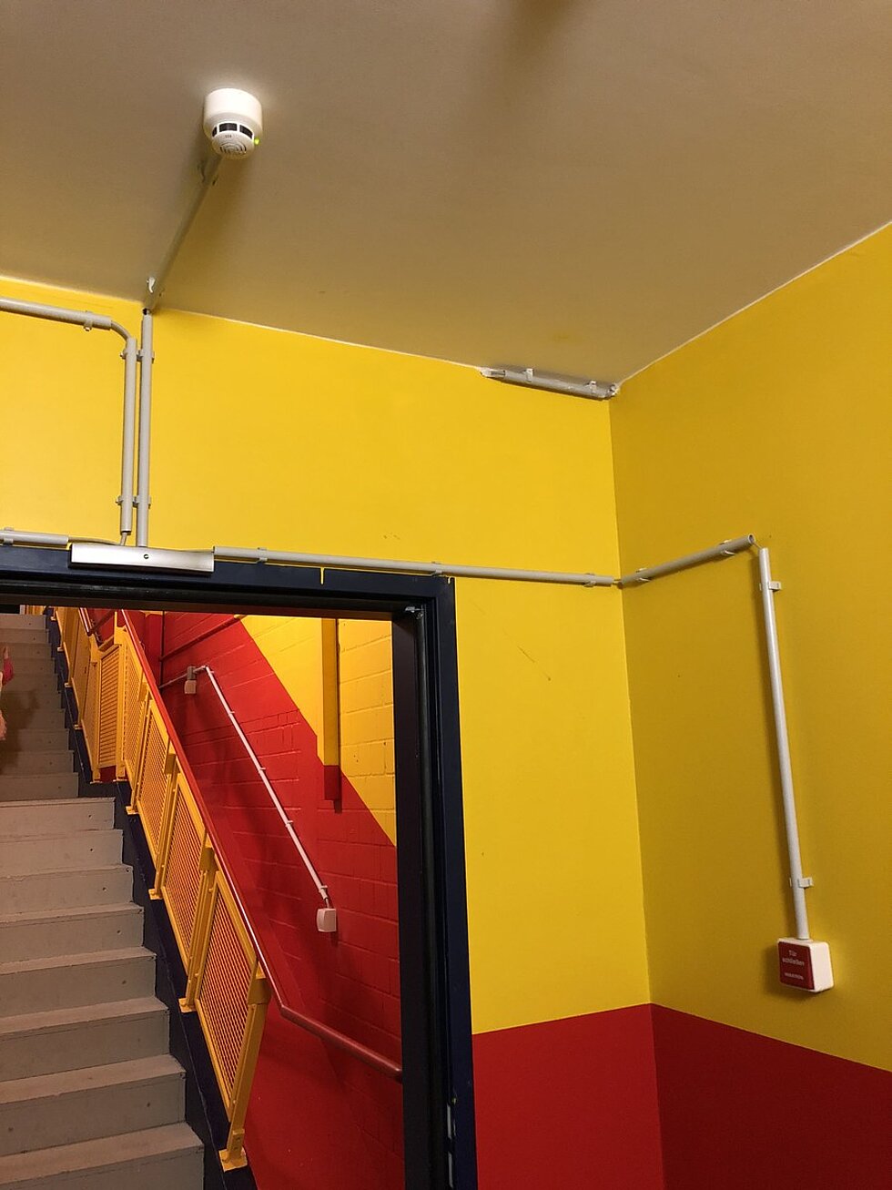 Deckenmelder einer Feststellanlage über einer Rauchschutztür im Treppenhaus